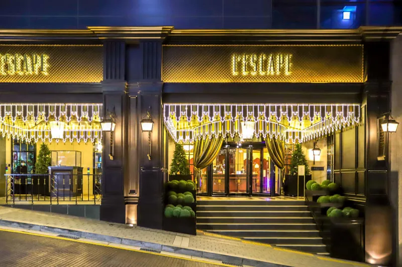 화려한 금빛 조명과 클래식한 디자인으로 장식된 레스케이프 호텔의 고급스러운 입구 모습입니다.